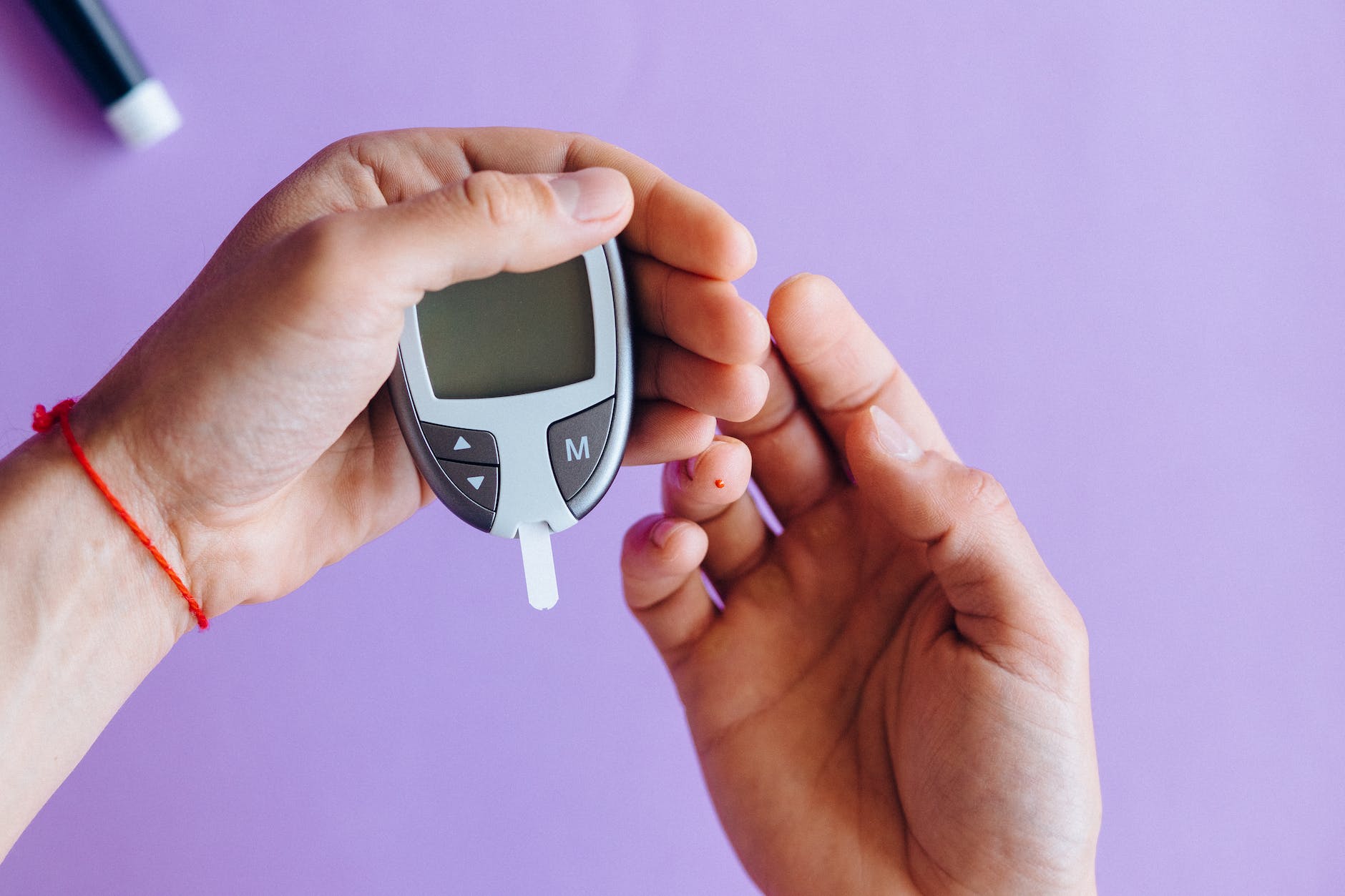 Picture of an individual using a glucometer to check their blood sugar level. 