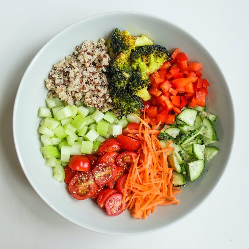 A picture of a healthy meal including cucumbers, broccoli, carrots, and quinoa. 